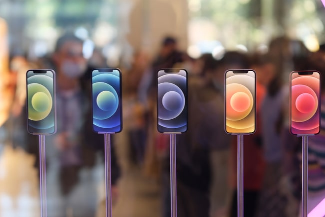 Fem färgglada Iphone 12-modeller på rad i en Apple-butik.