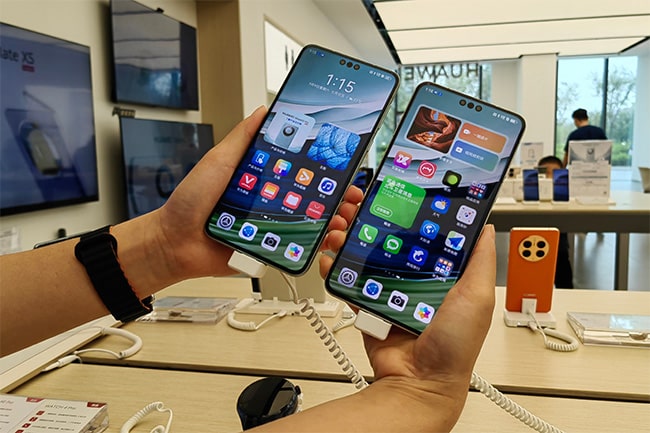Närbild på två händer som håller upp två huawei-mobiler med skärmen mot kameran.